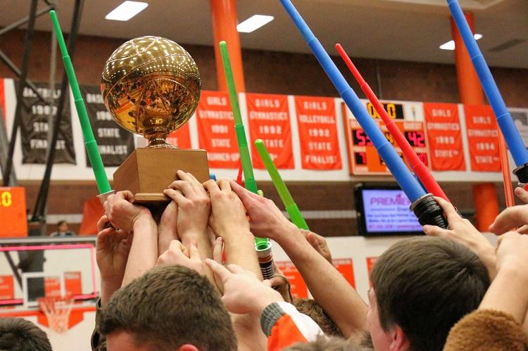 The Boys basketball team holds up the Hardwood Havoc Trophy after the win.