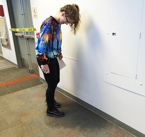 Senior Maelyn Kiser examines the water puddle on the floor on the third floor next to the T stairs. 