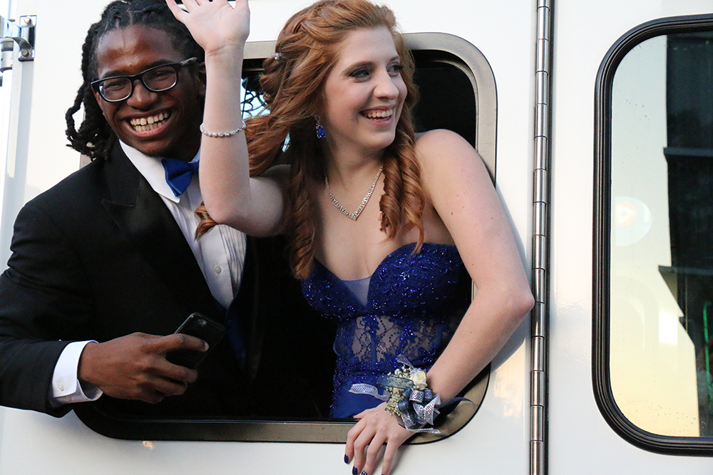 Junior Jamon Hogan and senior Conner Day wave through the prom parade in a firetruck.