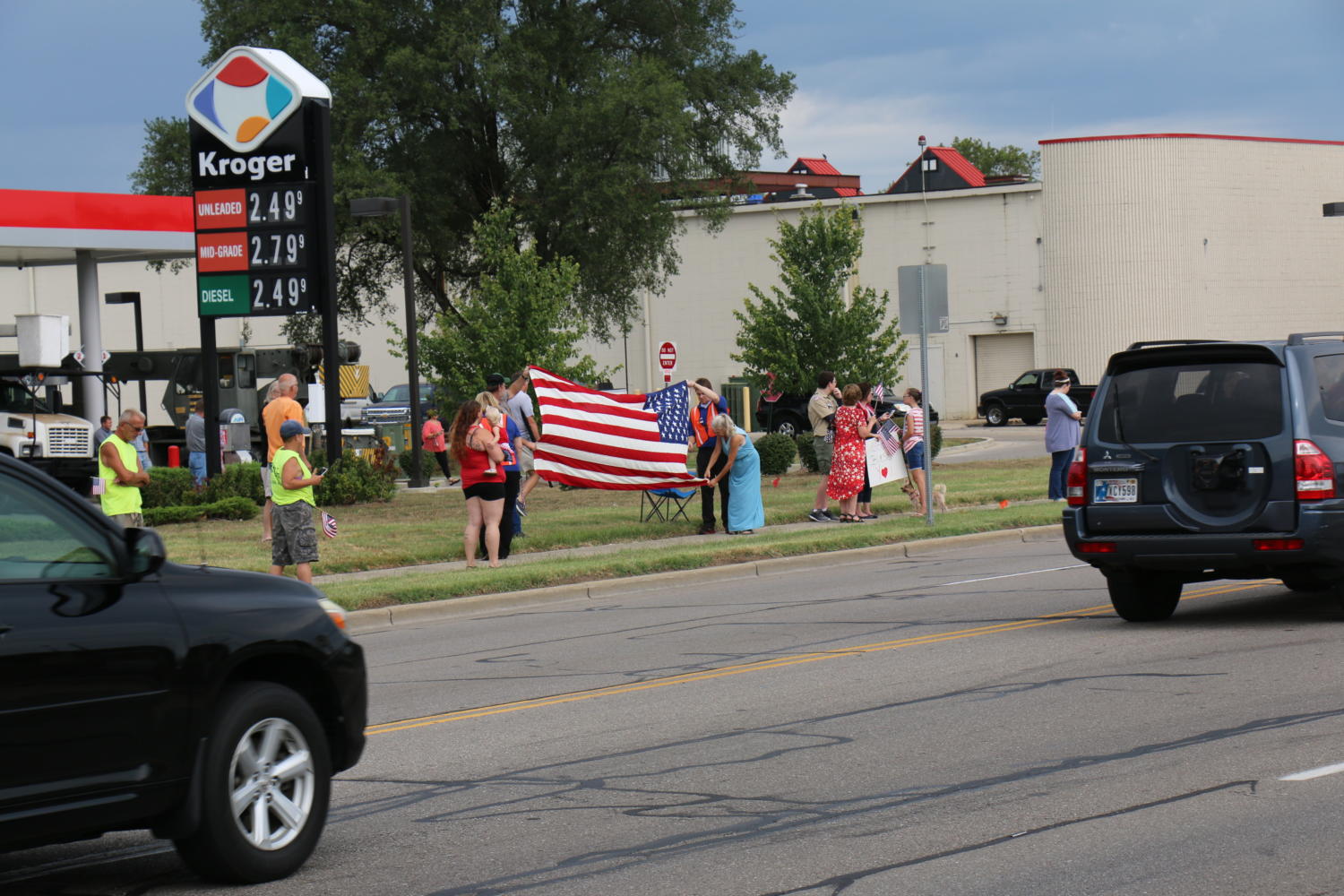 Community members display a large American flag as Sgt. Hunters funeral procession approaches.