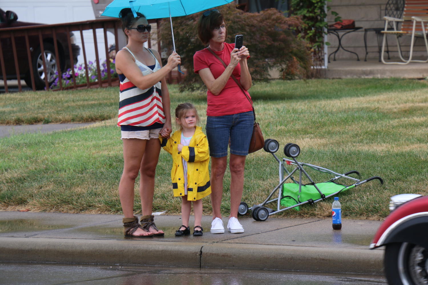 Community members take shelter under an umbrella as Sgt. Hunters funeral procession approaches.