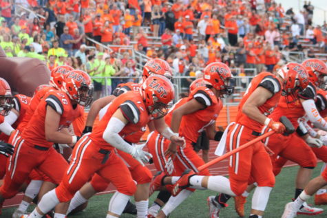 The Olympians run onto the field to kickoff the game.